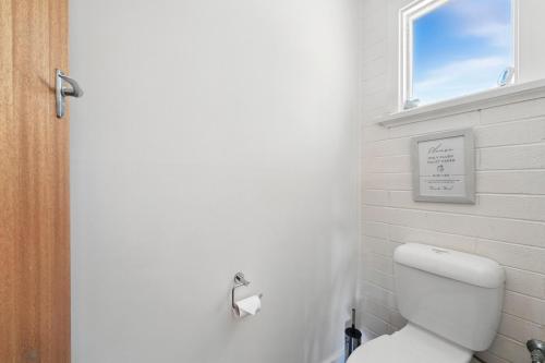 a bathroom with a white toilet and a window at Coningham Beach House - 3 Bedrooms in Coningham
