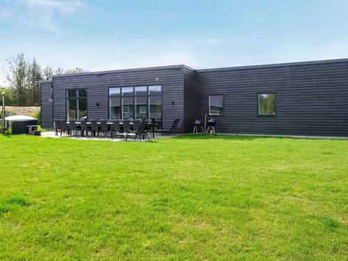 a black building with a lawn in front of it at 14 person holiday home in Glesborg in Glesborg