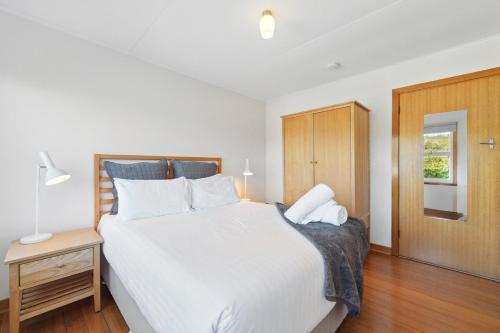a bedroom with a large white bed and a wooden cabinet at Coningham Beach House - 3 Bedrooms in Coningham