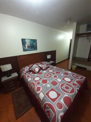 a bedroom with a bed with a red and white blanket at Hotel Central in Latacunga