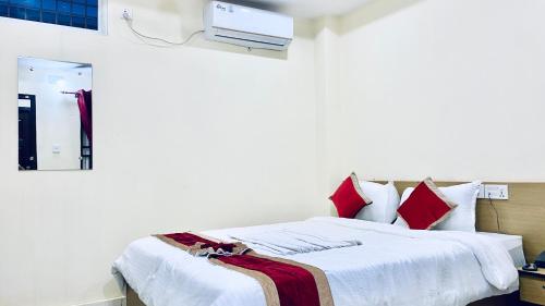 a bedroom with a bed with white sheets and red pillows at Hotel Kavya International in Bharatpur