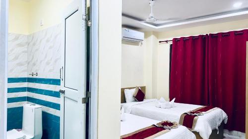 a room with two beds and red curtains at Hotel Kavya International in Bharatpur