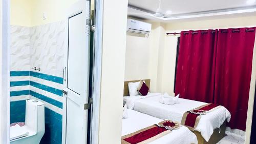 two beds in a room with red curtains at Hotel Kavya International in Bharatpur