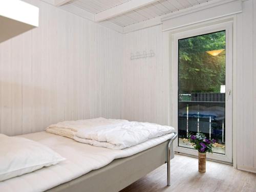 Una habitación blanca con una cama y una ventana. en Luxury Oasis near Grena Strand-By Traum, en Glesborg