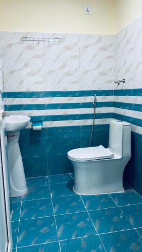 a blue and white bathroom with a toilet and a sink at Hotel Kavya International in Bharatpur