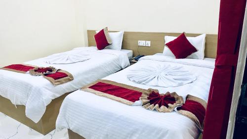 two beds in a room with red and white sheets at Hotel Kavya International in Bharatpur
