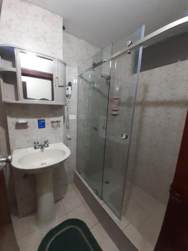 a bathroom with a glass shower and a sink at Hotel Central in Latacunga