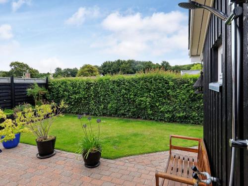 a patio with a bench and a green yard at 4 person holiday home in Assens in Assens