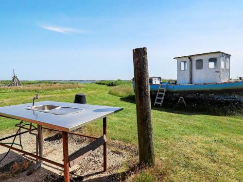 a table sitting in a field next to a boat at 20 person holiday home in Ulfborg in Ulfborg