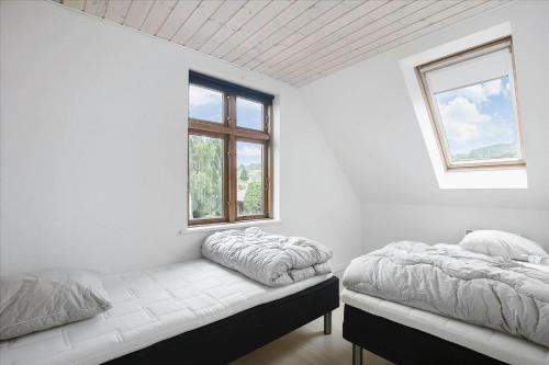 two beds in a white room with two windows at 6797-Allinge-Nordre-Strandvej-127 in Allinge