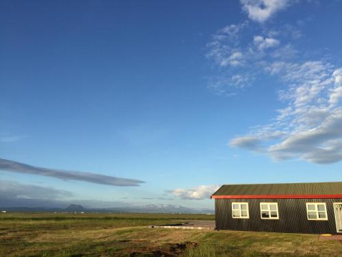 a barn in the middle of a field with a sky at Lindartún Guesthouse in Lindartún