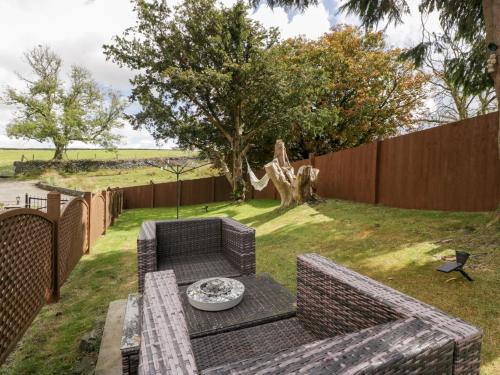 a backyard with a bench and a table and a fence at Caner Bach Lodge in Bridgend