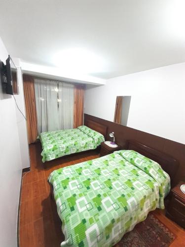 two beds in a room with green comforter at Hotel Central in Latacunga