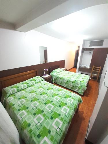 a bedroom with two beds with green comforter at Hotel Central in Latacunga