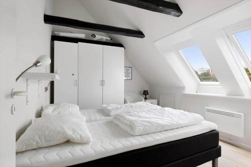 a white bedroom with a bed with white sheets at 5645-Gudhjem-Broddegade-14-lejl-13 in Gudhjem