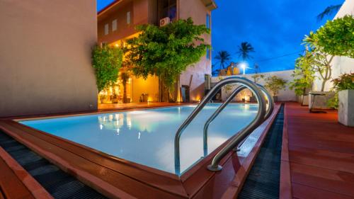 a swimming pool with a metal hand rail next to a building at Waves Hostel in Negombo