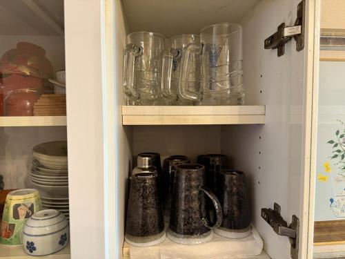a cupboard filled with glass jars and plates at Ikko's House in Ito