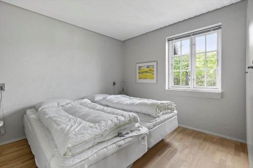 a white bedroom with a bed and a window at 5605-Ostermarie-Havrehojvej-10 in Østermarie