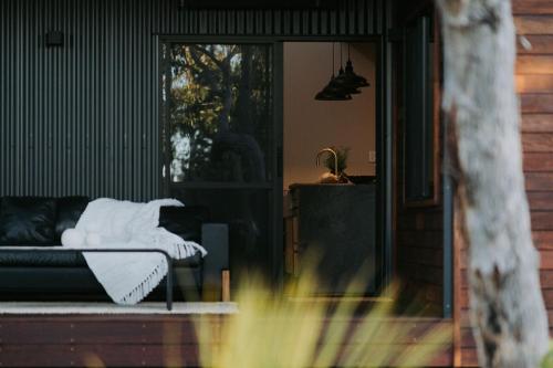 a couch with a white blanket sitting on a porch at Palmiera Escape - Luxury, laid-back holiday home in Margaret River in Margaret River Town
