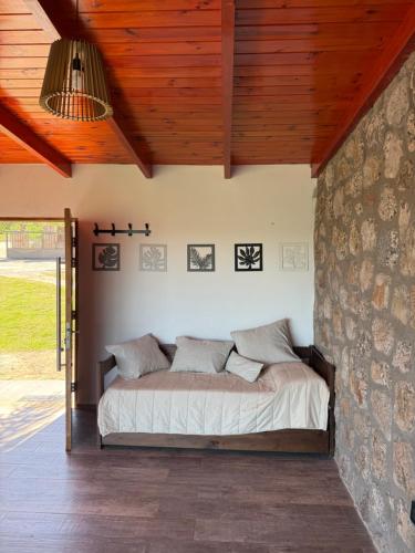 a bed in a room with a stone wall at EL PALMAR in Villa Carlos Paz