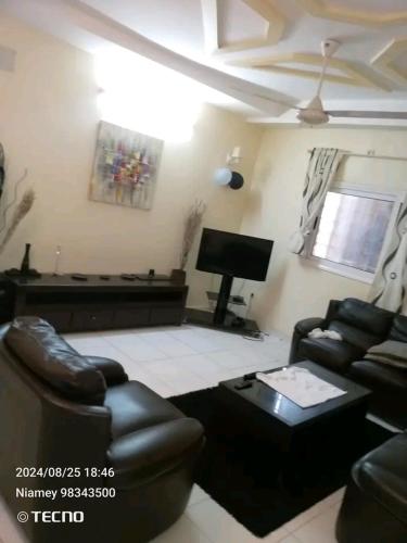 a living room with couches and a flat screen tv at Villa meublé Express in Niamey