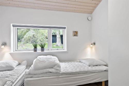 zwei Betten in einem weißen Zimmer mit Fenster in der Unterkunft 1435 Aakirkeby - Ædjavejen 10 in Vester Sømarken