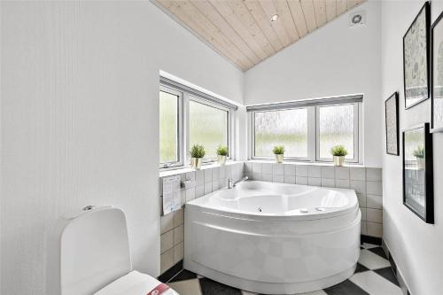 ein weißes Badezimmer mit großer Badewanne und Fenstern in der Unterkunft 1435 Aakirkeby - Ædjavejen 10 in Vester Sømarken