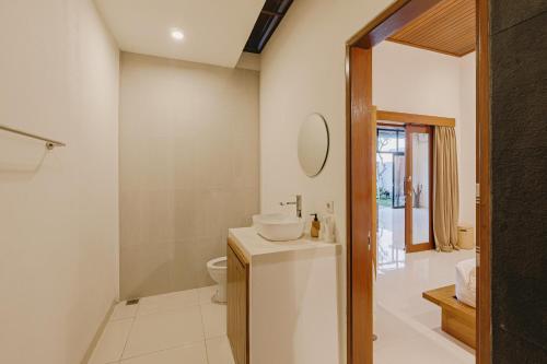 a bathroom with a sink and a toilet and a mirror at Arizona Villa by Betterplace in Cemagi