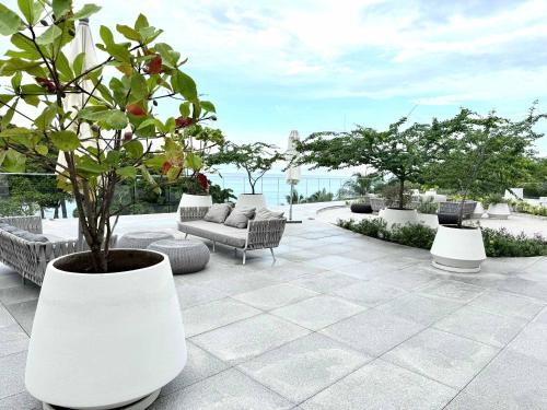 a patio with a tree and a couch and chairs at Bolongo 3BR your exclusive oceanfront escape in Punta Mita