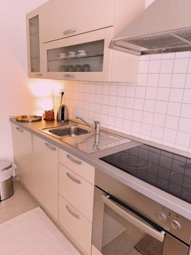 a white kitchen with a sink and a stove at Layal Home in Bihać