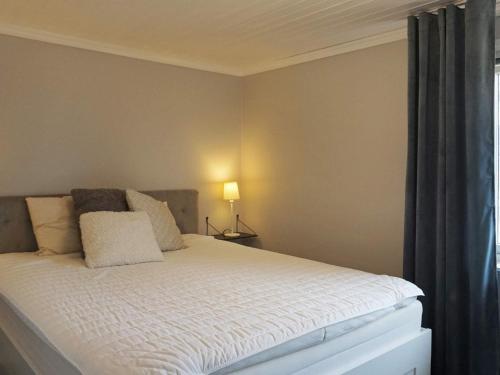 a bedroom with a bed with white sheets and a window at 5 person holiday home in Nösund in Nösund