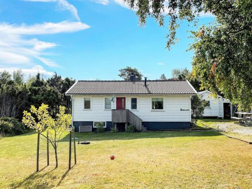 a white house with a red door in a yard at 5 person holiday home in Nösund in Nösund