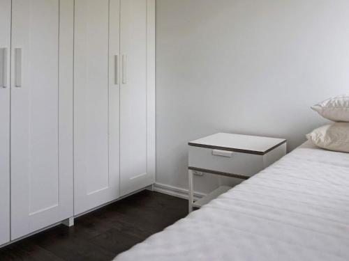 a white bedroom with a bed and a night stand at 5 person holiday home in Nösund in Nösund