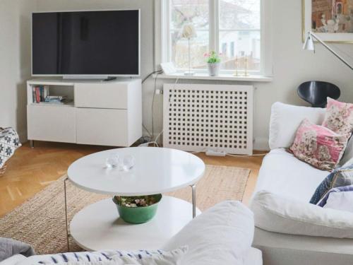 a living room with a white table and a tv at 5 person holiday home in BÅSTAD in Båstad