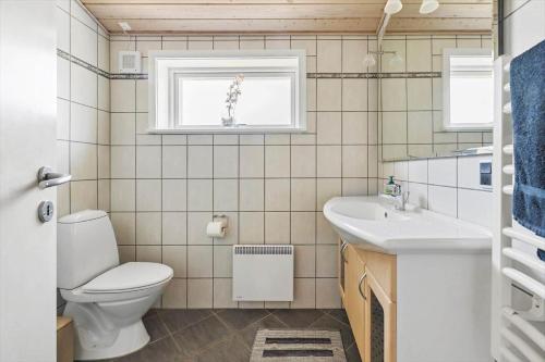 a bathroom with a toilet and a sink and a window at 3712-Nexo-Aastien-8 in Neksø