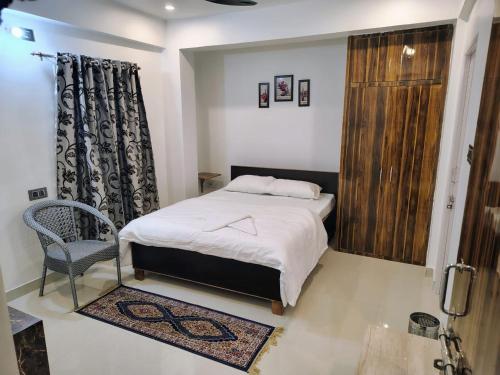 a small bedroom with a bed and a chair at Magadh Homestay in Patna