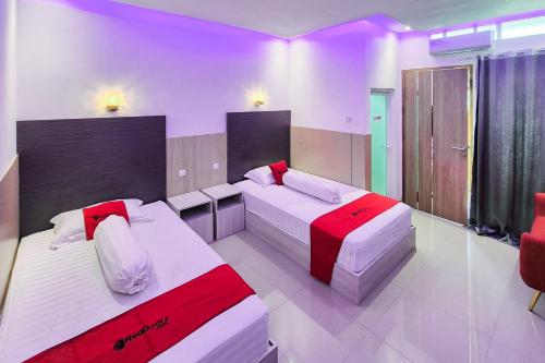 a bedroom with two beds with red and white pillows at RedDoorz near Mutiara SIS Al Jufrie Airport Palu 3 