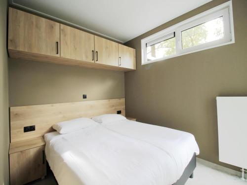 ein Schlafzimmer mit einem großen weißen Bett und einem Fenster in der Unterkunft Modern Lakeview Cottage in Veluwe in Hoenderloo