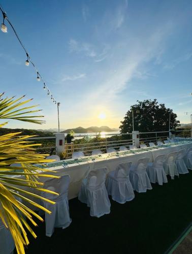 a long white table with white chairs and the sunset at Asia Grand View Hotel in Coron