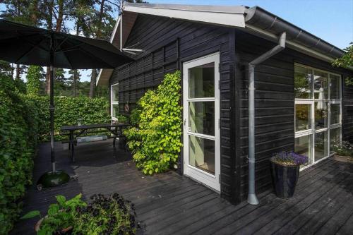 a black house with an umbrella on a deck at HA318-Hals-Merkurvej-73 in Hals