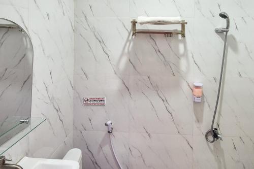 a white bathroom with a shower and a toilet at RedDoorz near Mutiara SIS Al Jufrie Airport Palu 3 