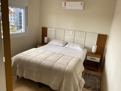 a bedroom with a large white bed and a window at 2 suítes - 7 lugares, sua família prox Catedral de Pedra in Canela