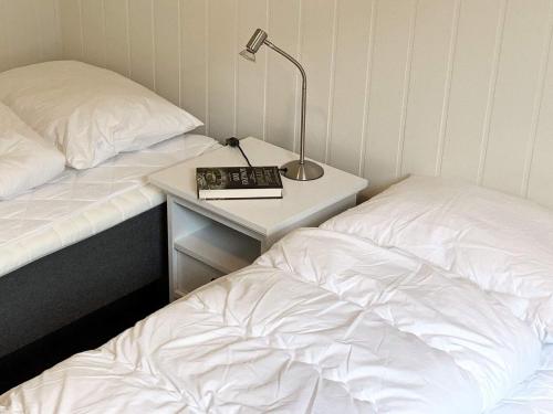 a bedroom with two beds and a night stand with a lamp at 8 person holiday home in Urangsvåg in Ervik