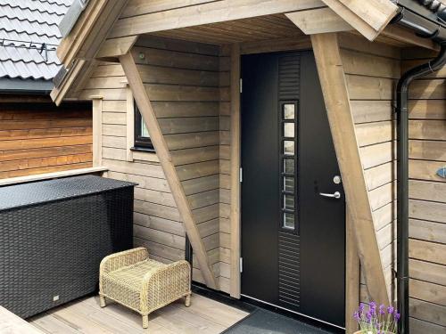 a porch with a black door and a wicker chair at 8 person holiday home in Urangsvåg in Ervik