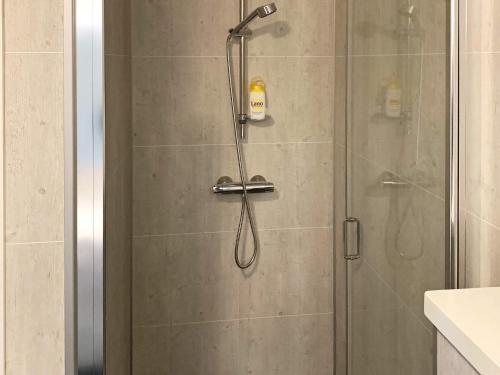 a shower with a glass door with a shower head at 8 person holiday home in Urangsvåg in Ervik