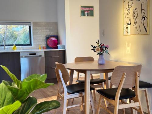 a kitchen with a table and chairs with a vase of flowers at Colour Burst Townhouse in Christchurch