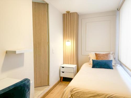 a small bedroom with a bed with a blue pillow at Hotel Santa Elena Norte in Tunja
