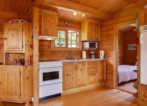 a kitchen with wooden cabinets and a stove in a cabin at LF21543-Spottrup-Tyttebaervej-10 in Lem