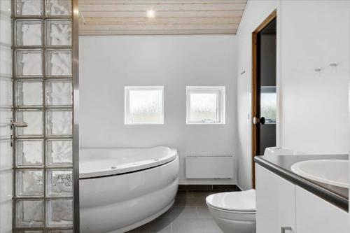 a white bathroom with a tub and a toilet at LF15198-Hojslev-Bronzehojen-7 in Højslev