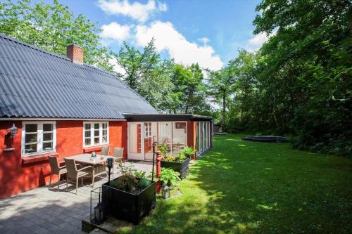 a small red house with a table and chairs in a yard at LF11124-Struer-Vesterkaervej-24 in Struer